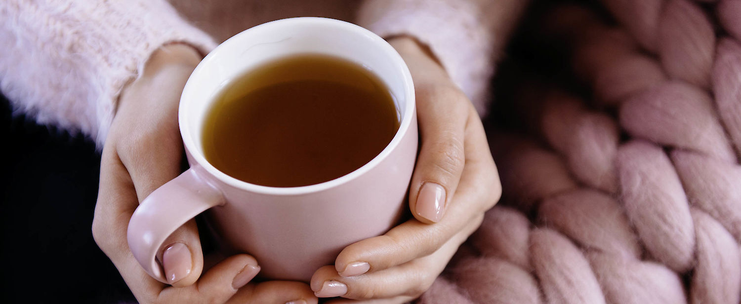 Frau hält eine Teetasse in den Händen