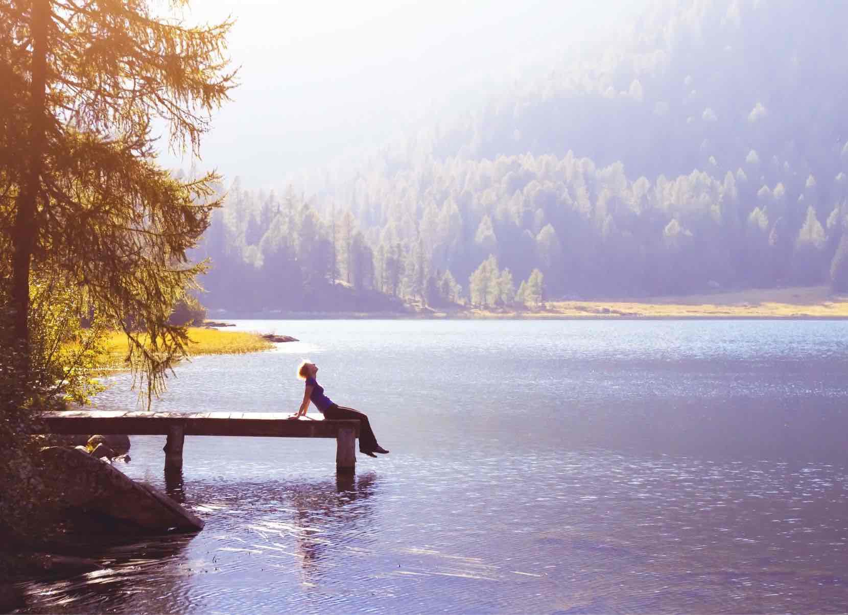 Eine Frau sitzt auf einem Steg an einem See