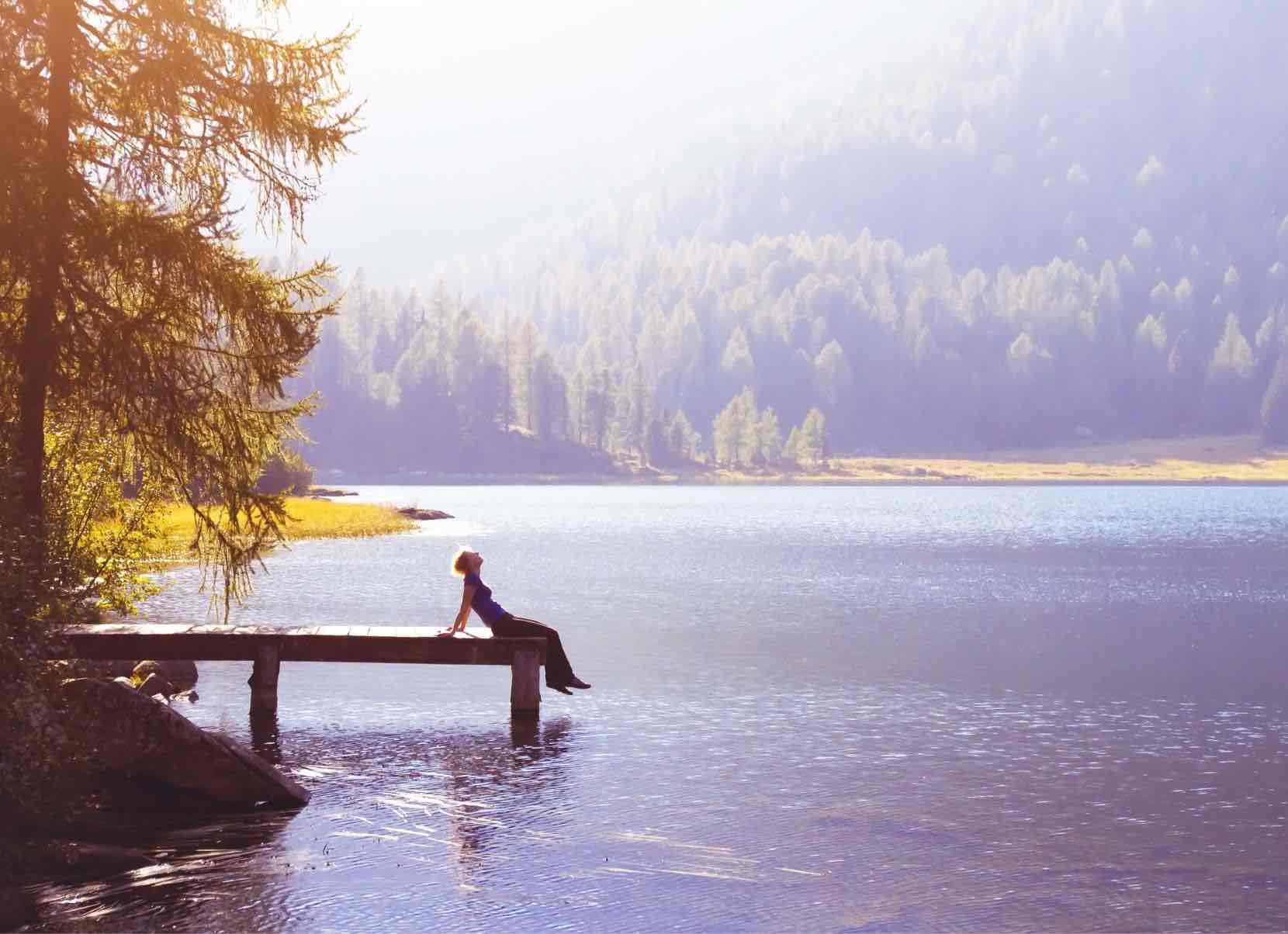 Eine Frau sitzt auf einem Steg an einem See