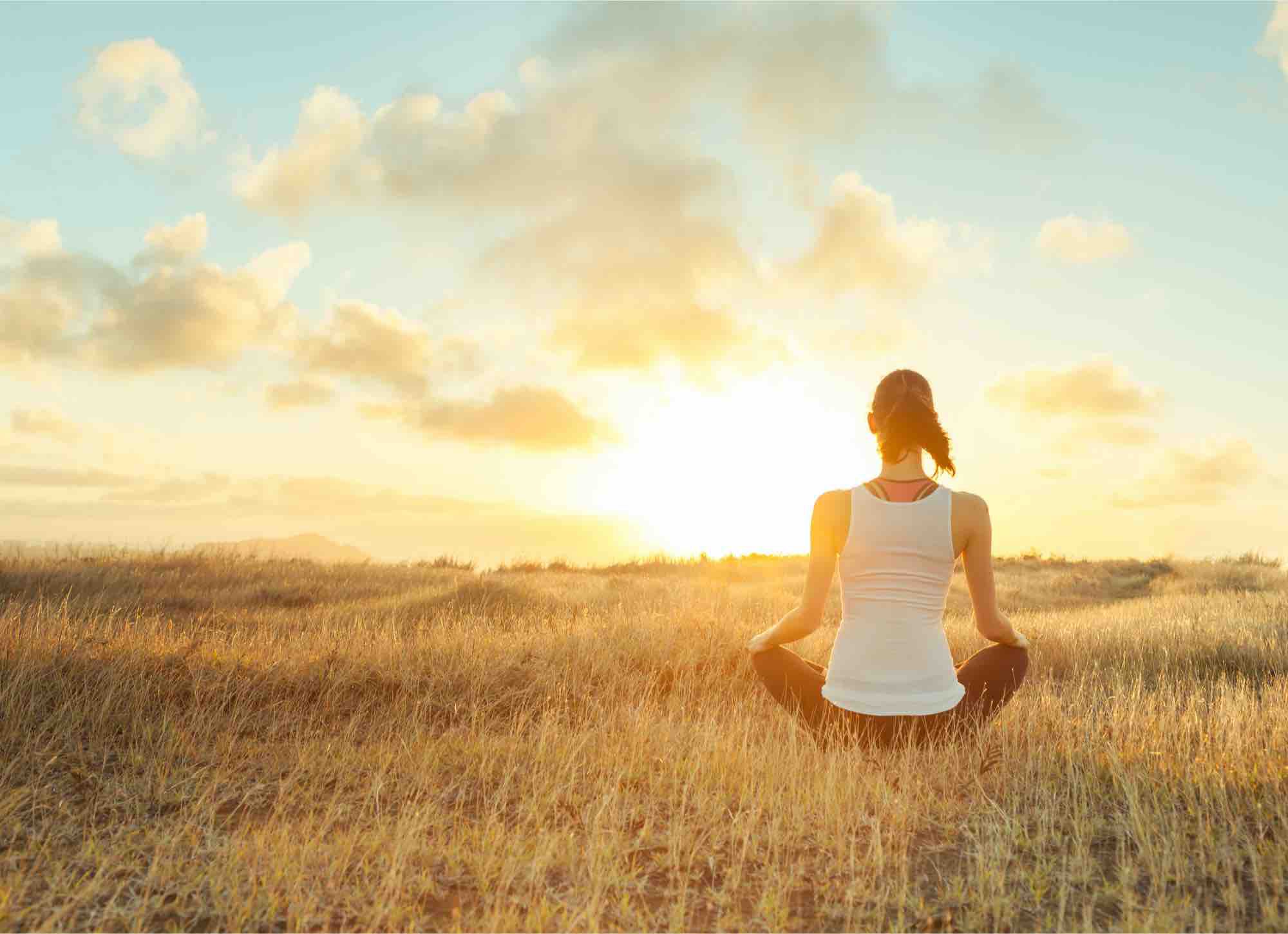 Eine Frau meditiert bei Sonnenaufgang