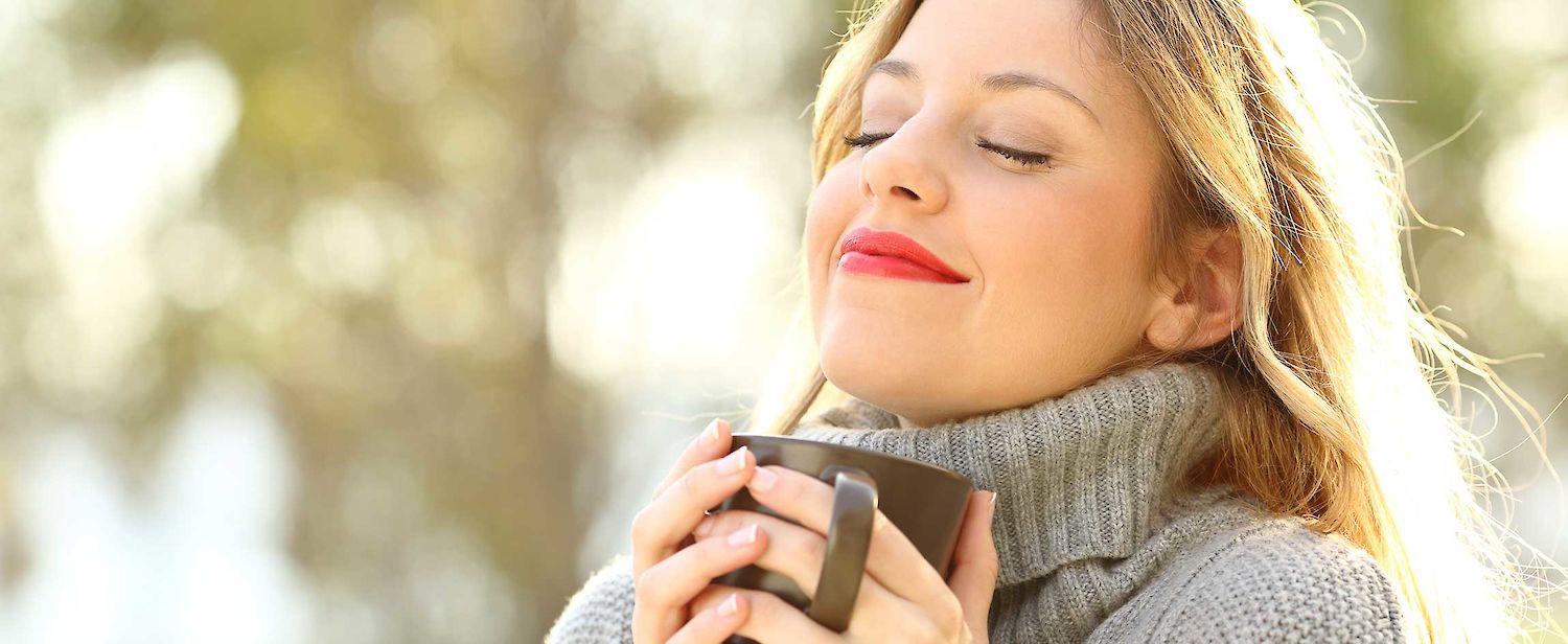 A woman drinks YOGI® Beautiful Skin and smiles.